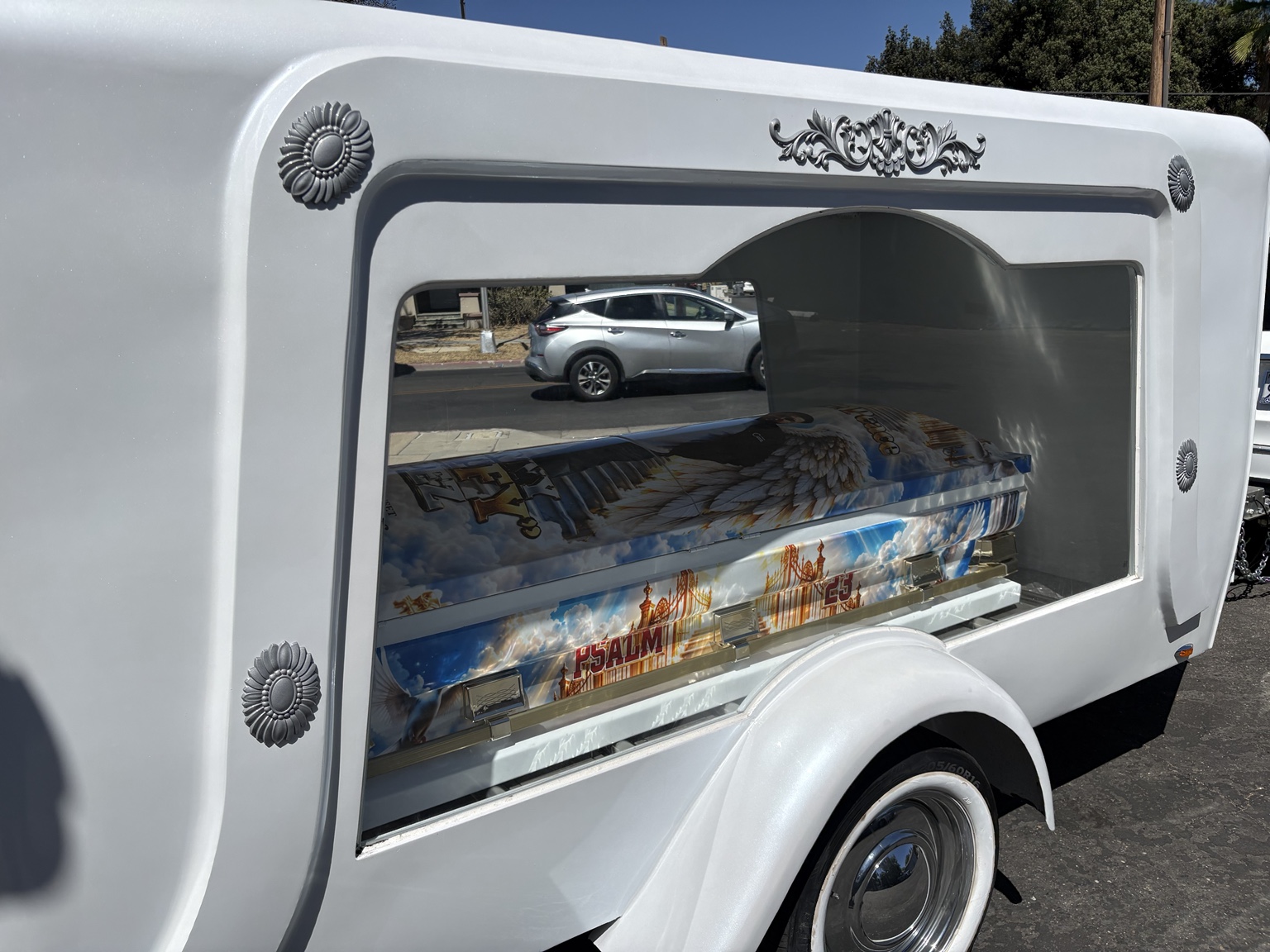 Side view of white hearse trailer displaying custom memorial casket