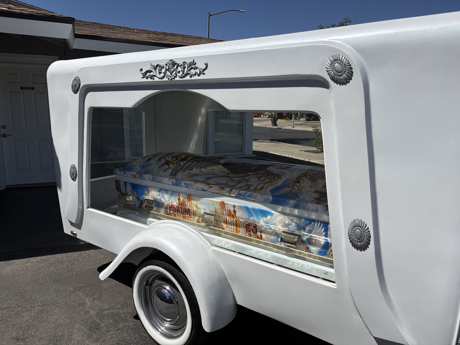 White hearse trailer with personalized casket visible through side window